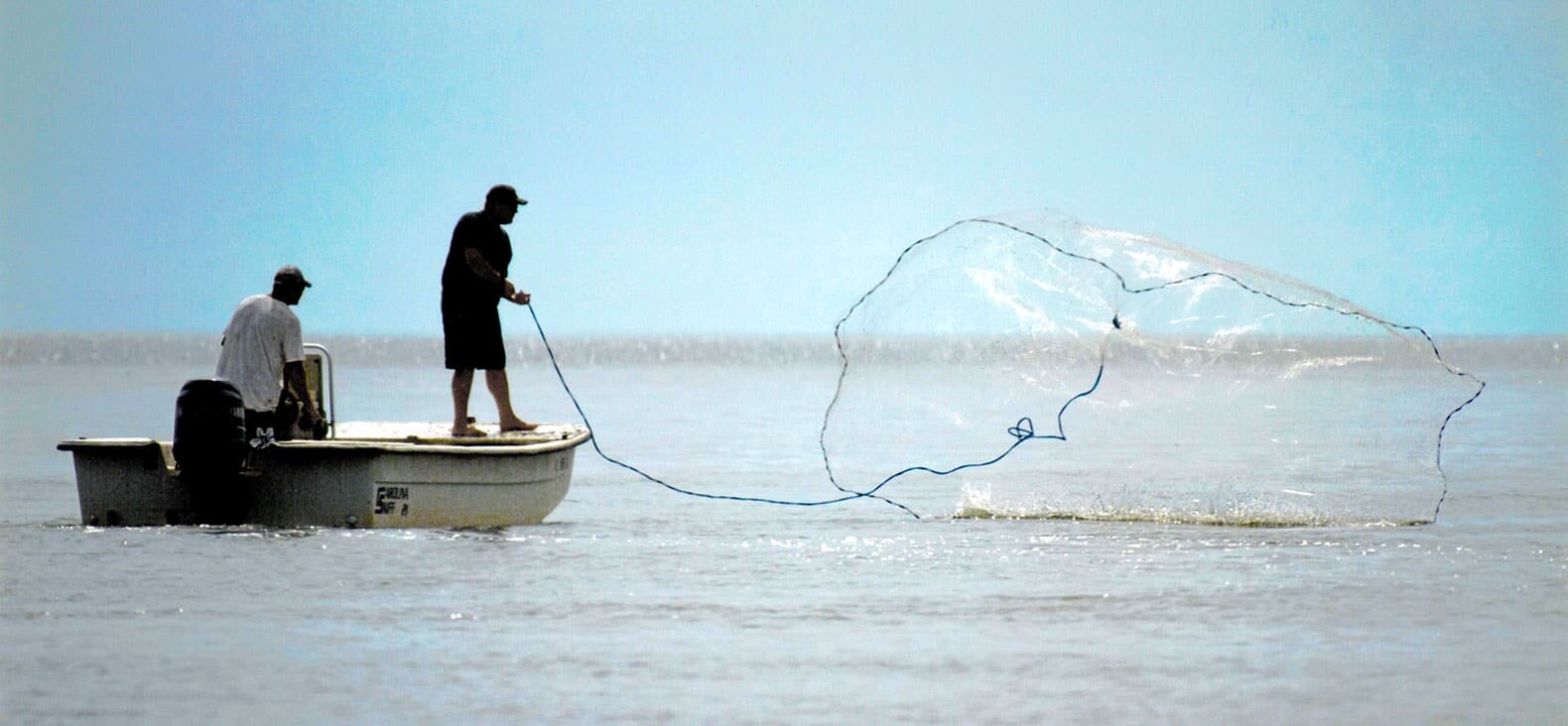 Two men on a boat fishing.